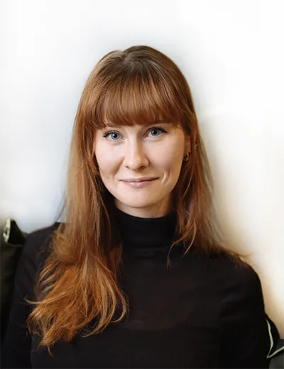 Foto mit einem Porträt von Dina Brandt in einem schwarzen Rollkragenpullover vor weißem Hintergrund